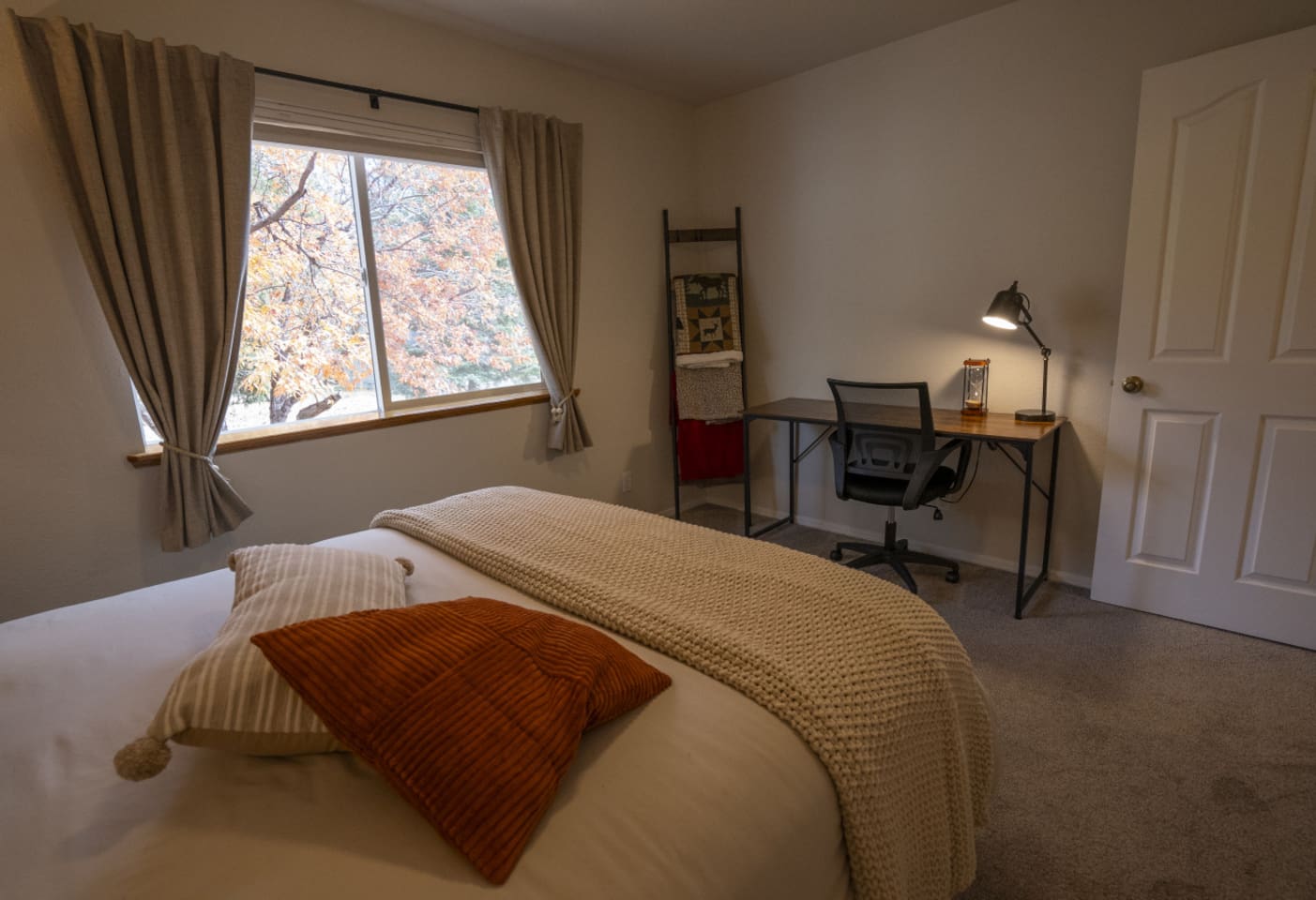 Queen bedroom with soft bedding, and a small desk perfect for working.