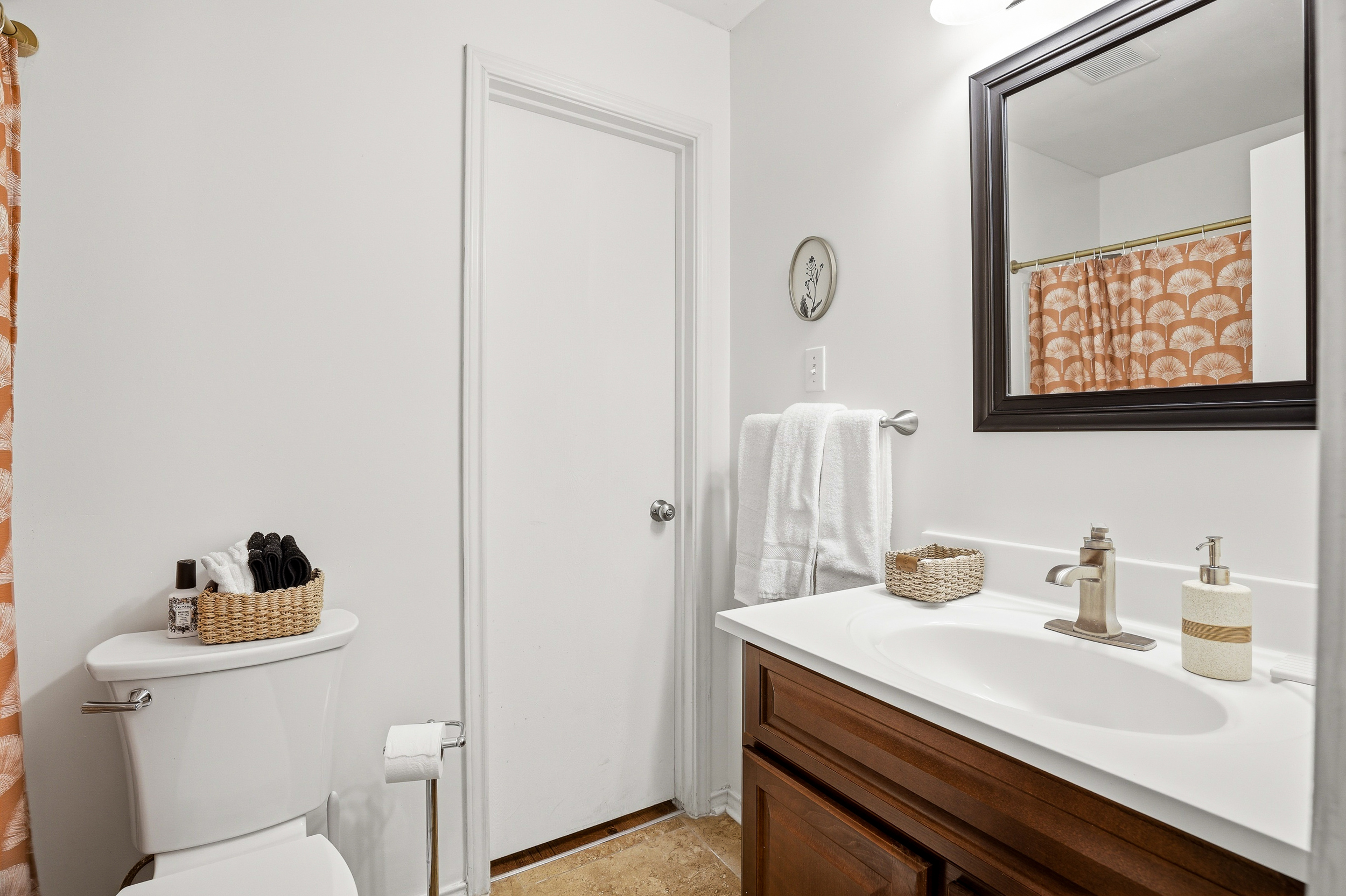 Second full bathroom with dark wood vanity, white countertop, fresh towels, and toiletry basket. Shower and tub combo keeps both bathrooms fully functional for groups of up to 6.
