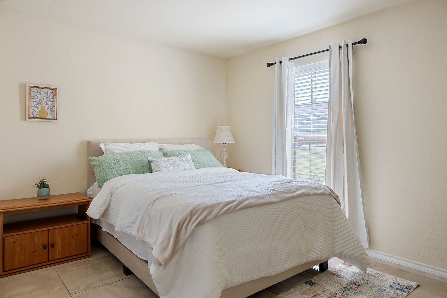 Enter this cozy bedroom, which features beautiful wall art, a bedside lamp, and a comfortable bed.