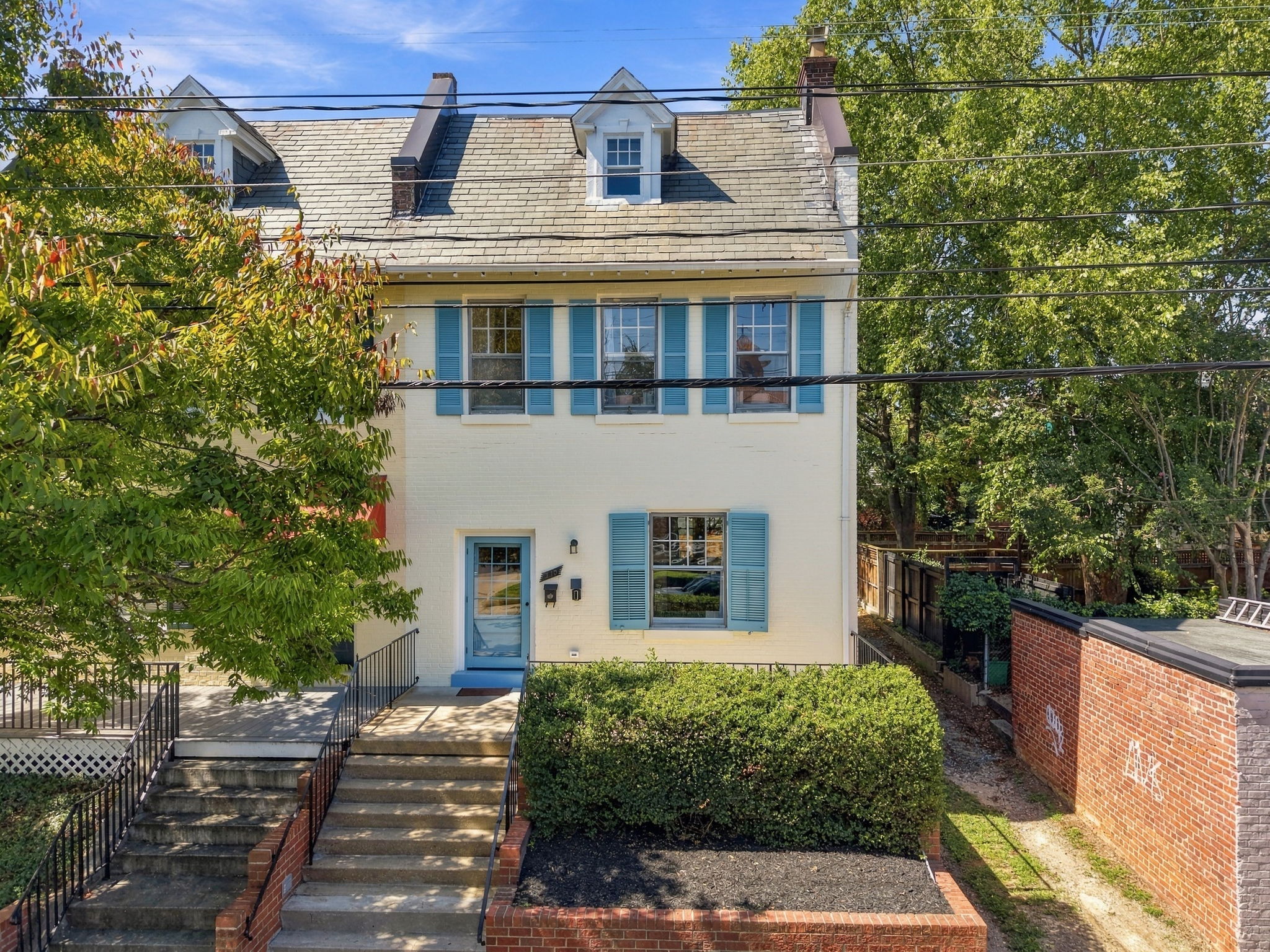 Exterior: Charming brick facade with vibrant blue shutters and inviting garden steps await!