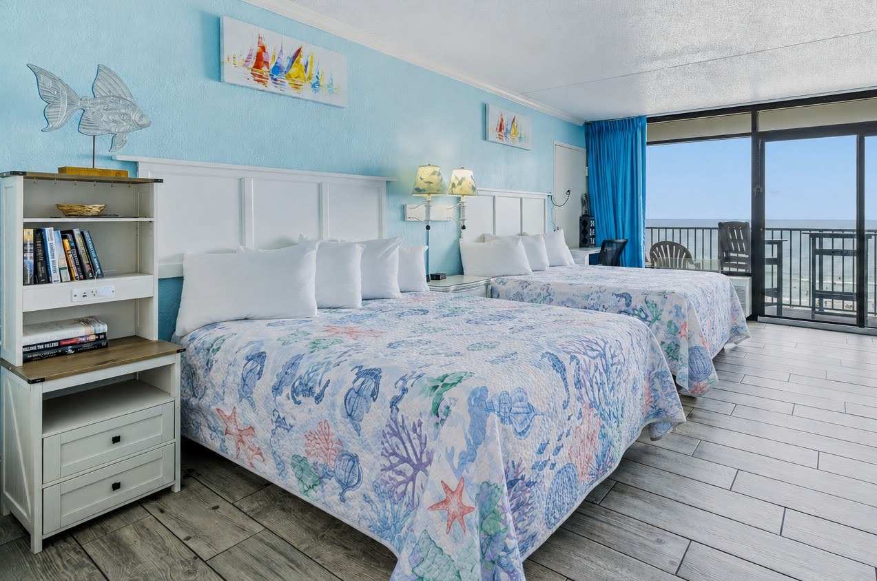 Two beds, a shelf of good reads, and the ocean waiting at the end of the room. ⭐