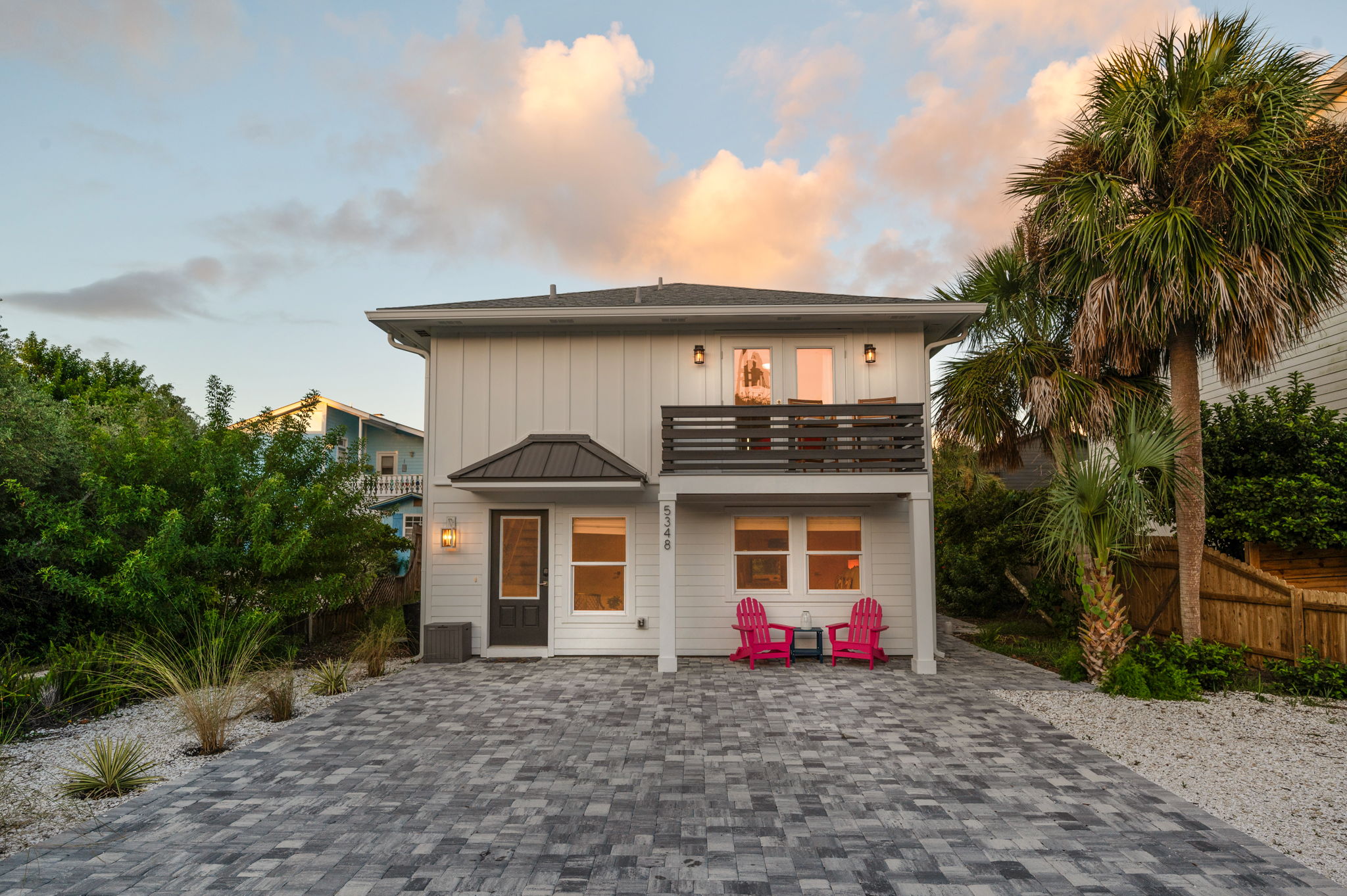 Here’s a beautiful sunset shot, with golden hues and fluffy pink clouds. Below, you can spot two pink chairs nestled under the outdoor balcony, which also features a cozy seating area. This serene space is just off the master bedroom suite 