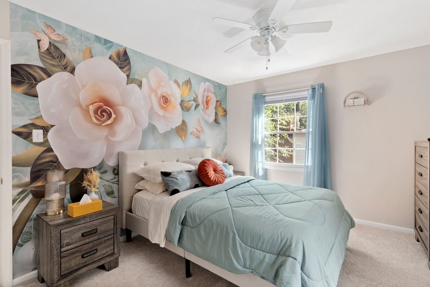 Whimsical and spacious bedroom featuring custom floral mural, queen bed, and plenty of natural light.