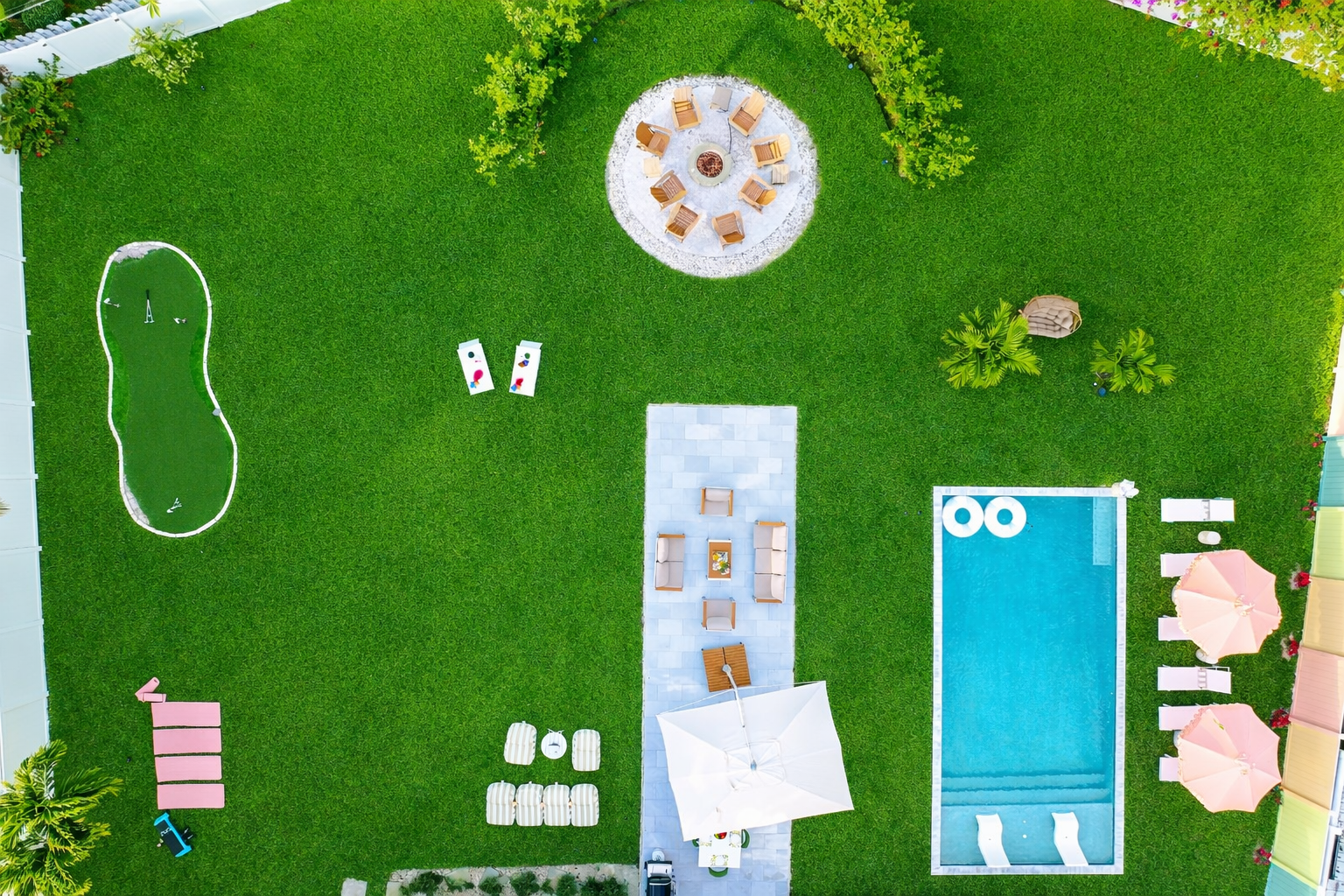 Private Palm Beach backyard with heated saltwater pool, fire pit, mini golf putting green, and outdoor lounge seating.