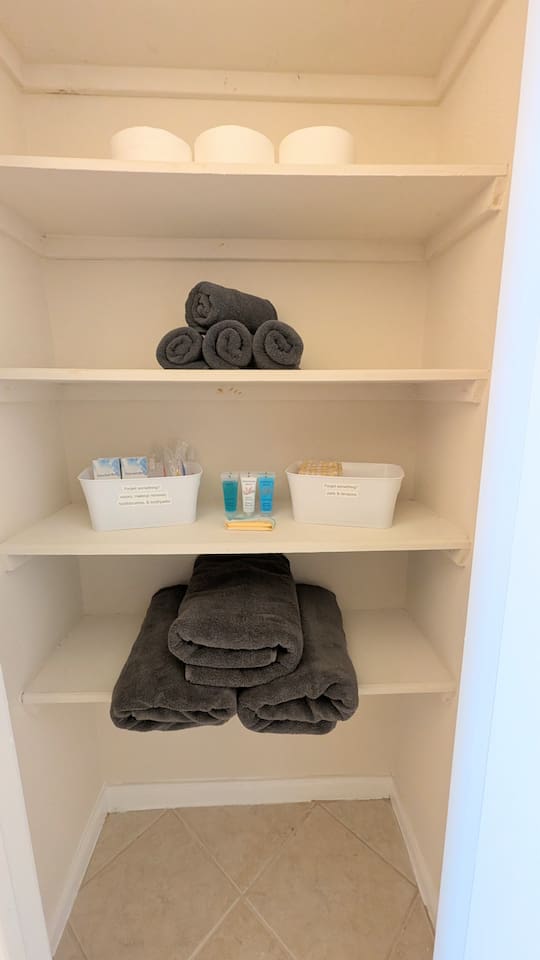 Well stocked linen closet includes extra toilet paper, towels, and essential toiletries. 