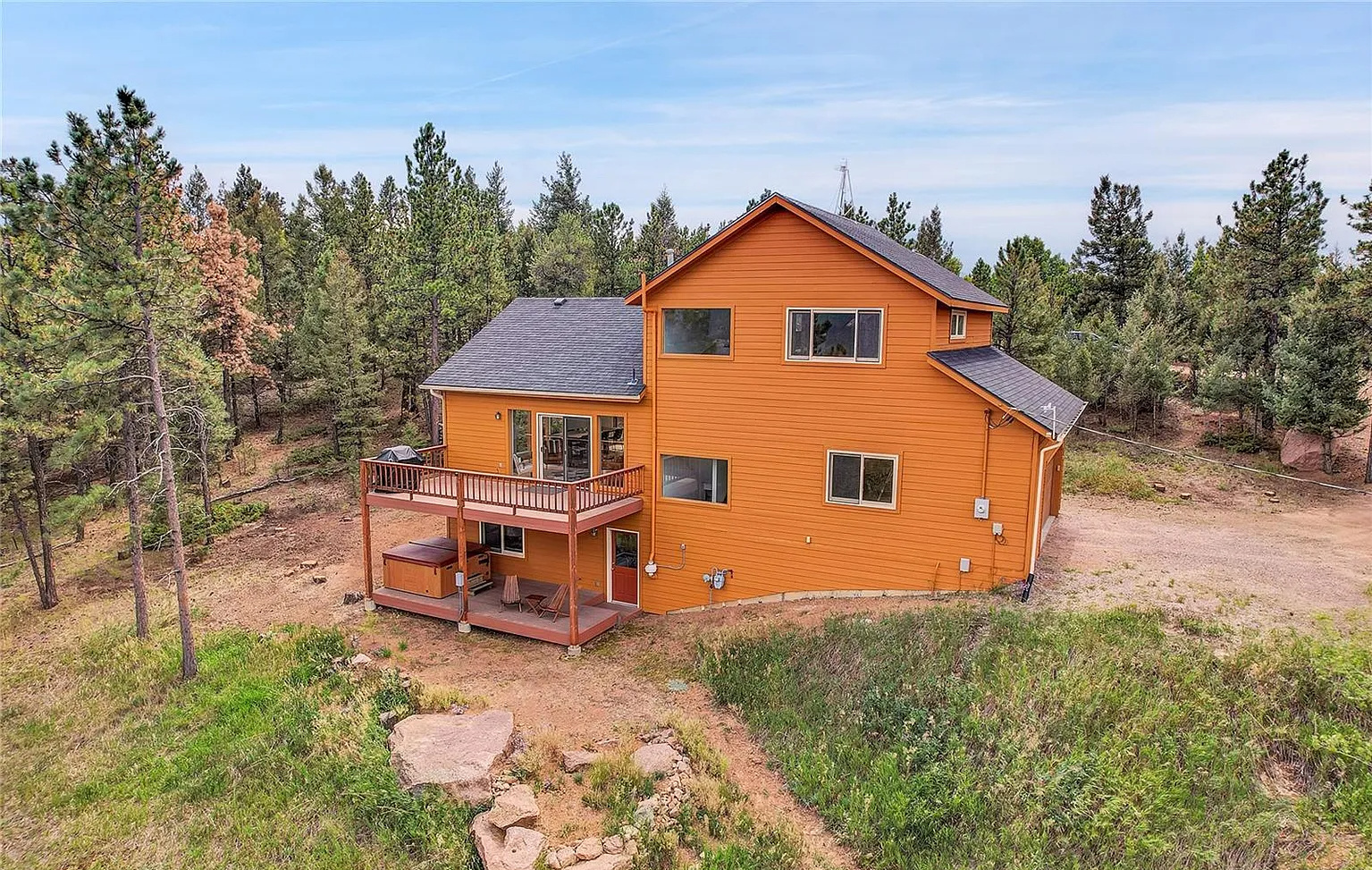 Rear exterior view highlighting the spacious multi-level deck and mountain backdrop.
