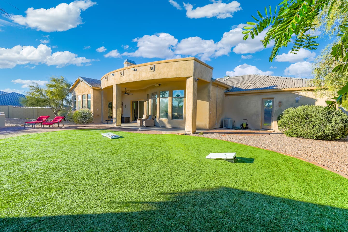 Expansive backyard view highlighting the covered patio, artificial turf, and seamless indoor-outdoor flow.