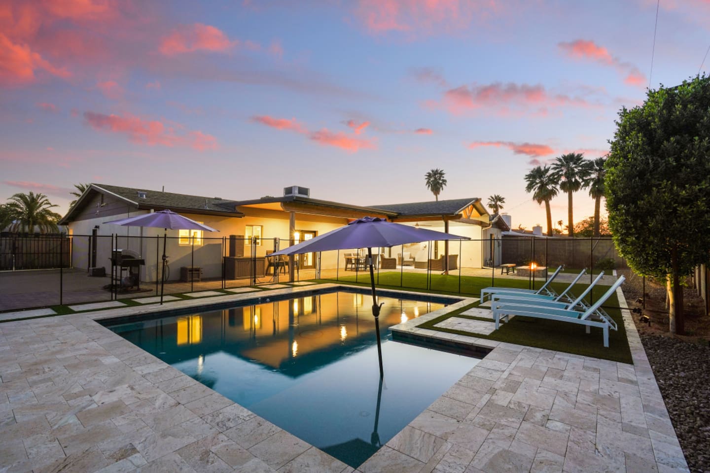 Private backyard pool with lounge chairs, umbrella shade, fire pit seating, and a bright outdoor space 