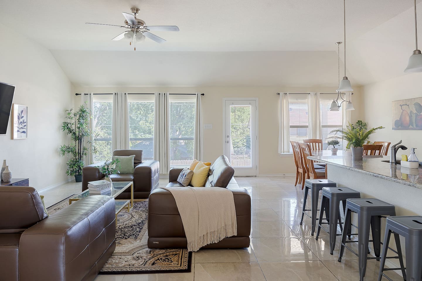 Delight in the spacious living room with plush leather sofas and an open floor plan leading to a modern kitchen with a breakfast bar.