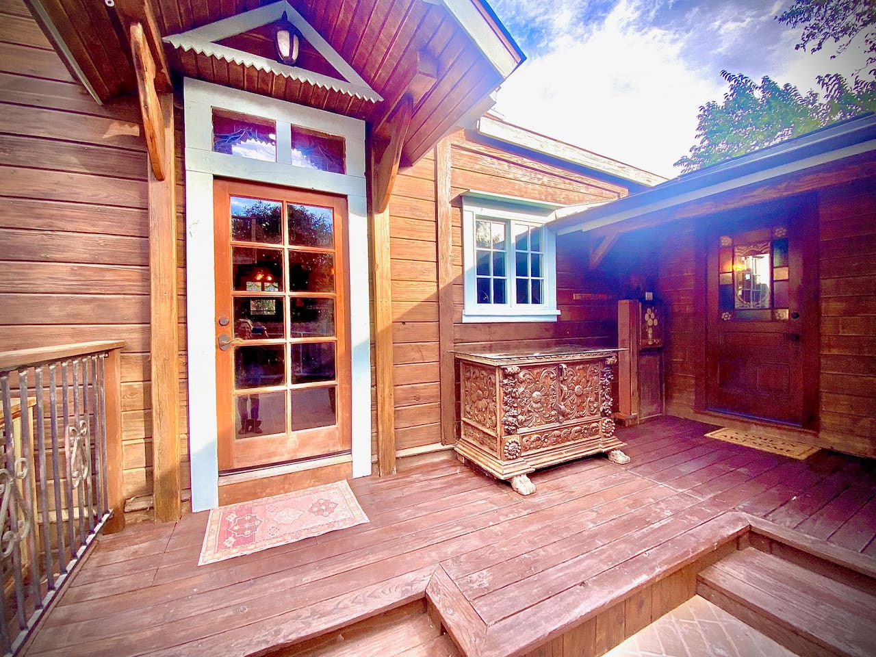 This sheltered porch is the home’s indoor-outdoor crossroads: the glass door leads to the kitchen, while the restored stained-glass door opens to the Bath Annex and two powder rooms—an especially thoughtful flow for groups and approved events.