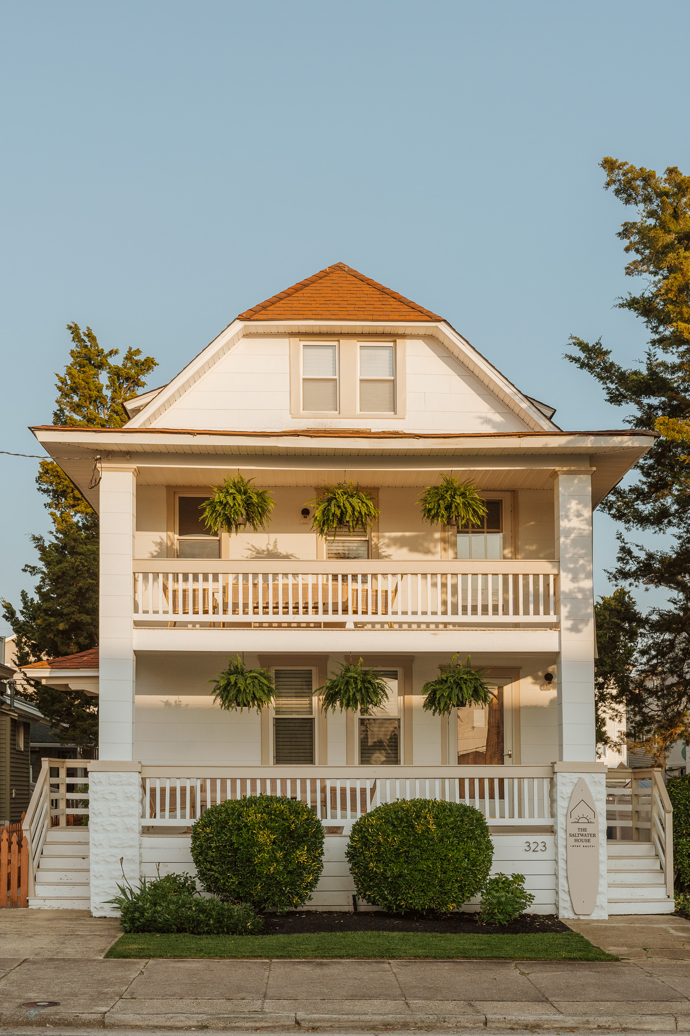 Wide Front Exterior Shot Displaying Multi-Level Covered Porches and Lawn