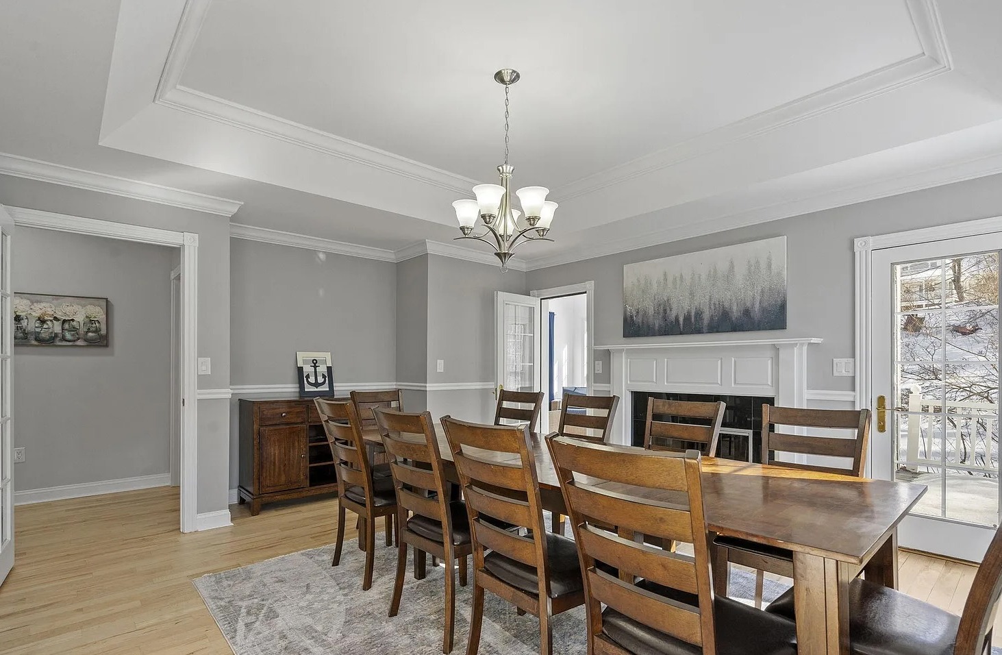 This inviting dining room comfortably seats 10 guests and features a stunning fireplace along with expansive windows that fill the space with natural light.