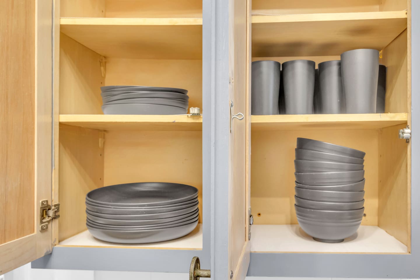 Kitchen cabinet stocked with plates and dining essentials.