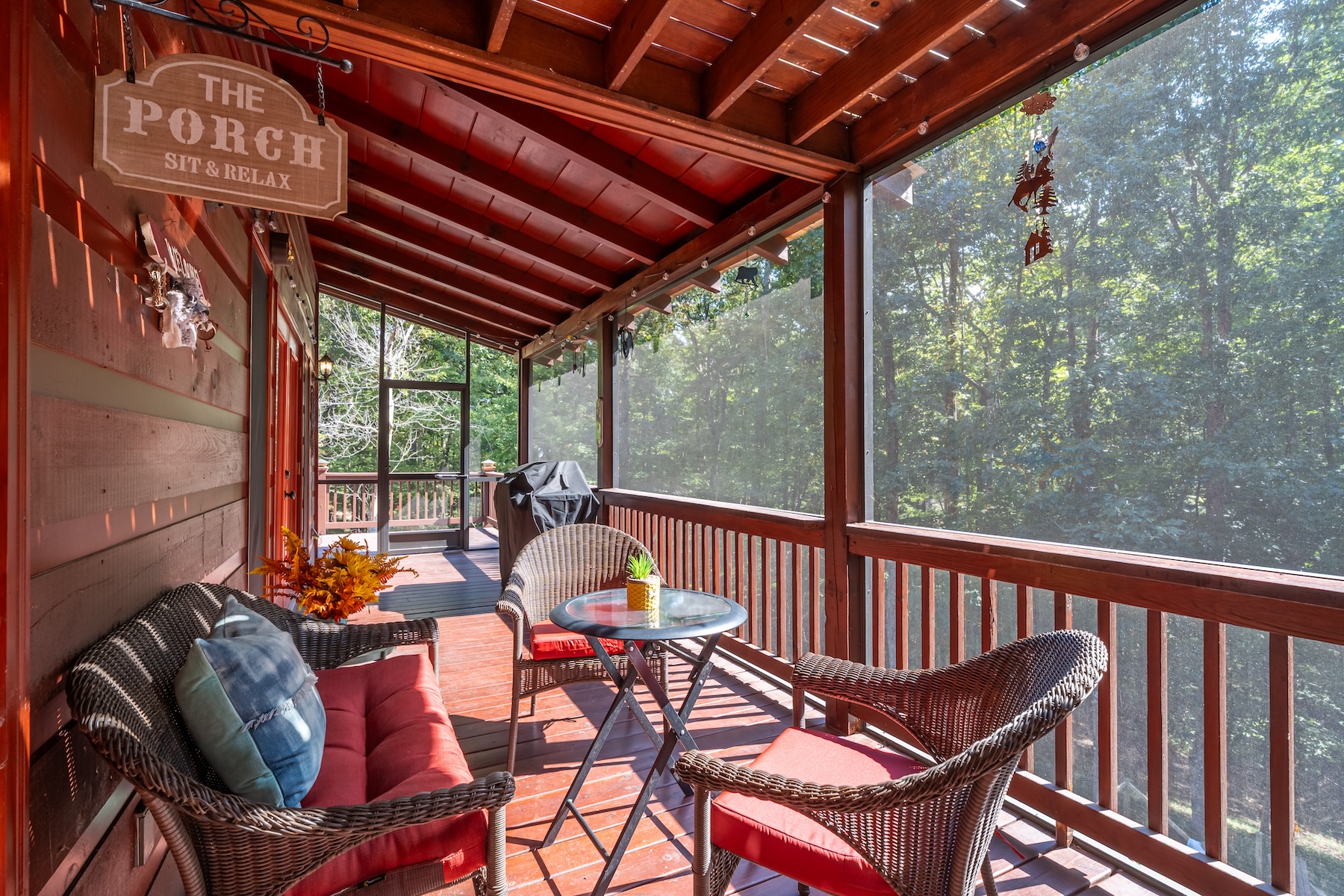 Screened back porch with swing, comfy seating, BBq grill with propane tank and storm door leading to wrap around deck and to the front door.