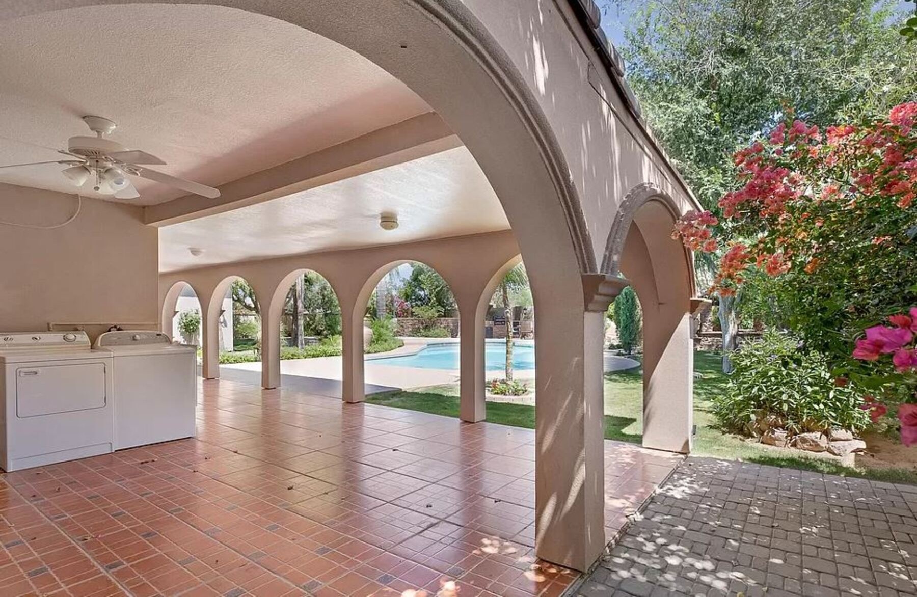 Lounge beneath graceful arches with views of the sparkling pool and blooming desert flowers in this serene outdoor living space.
