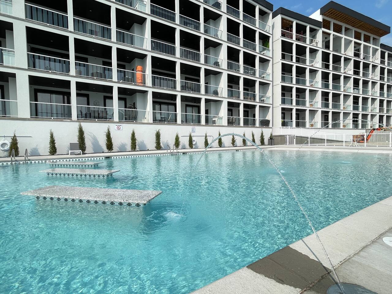 One of two pools for guests. Tables in the deep end with beach entry design in the shallow end, with spraying fountains. 