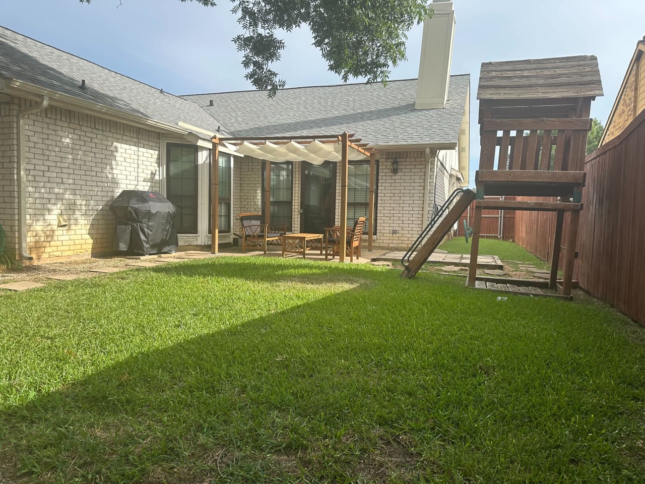 Private backyard with shaded seating and playset — ideal for family fun.
