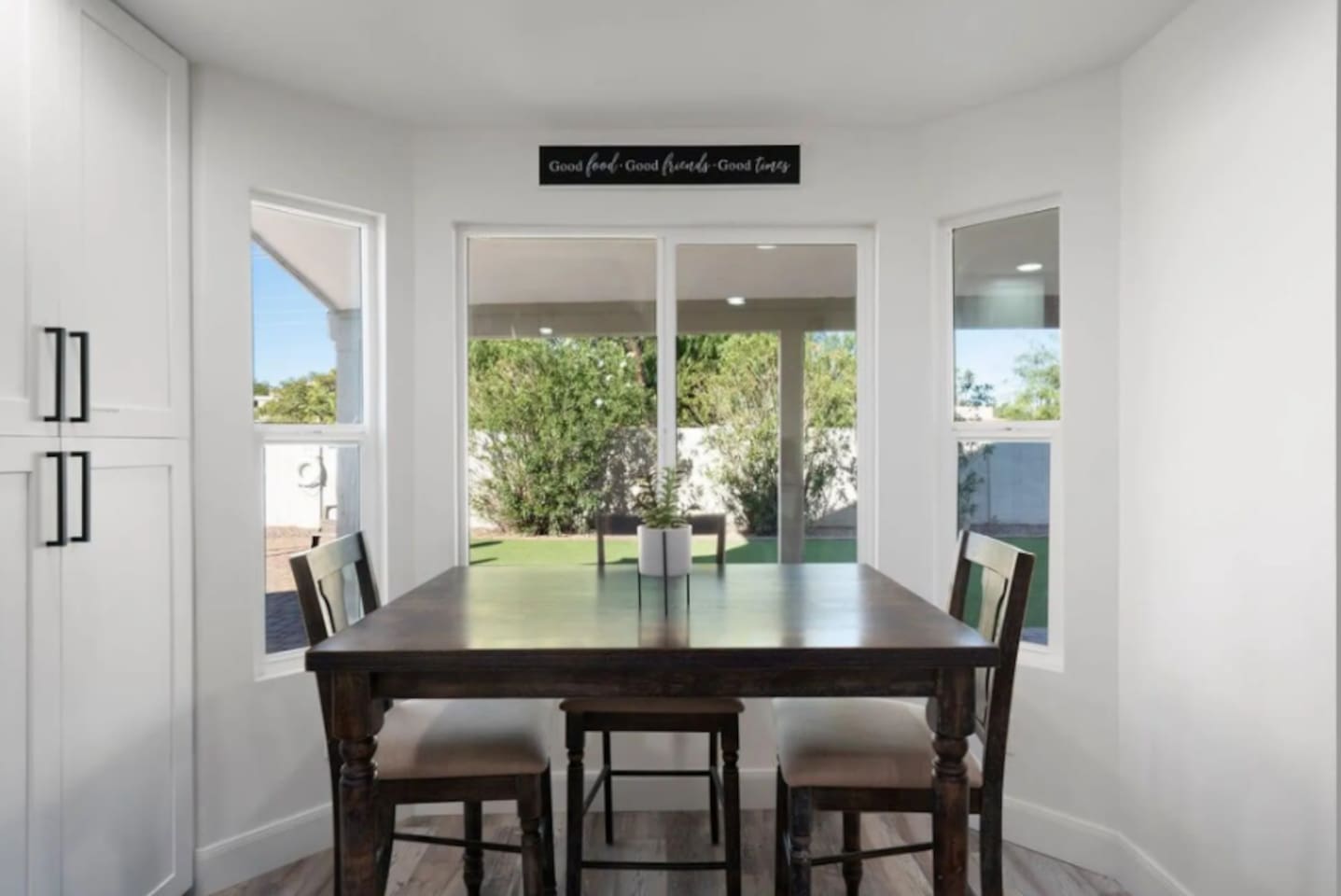 Bright dining area with expansive glass windows with manicured backyard views.