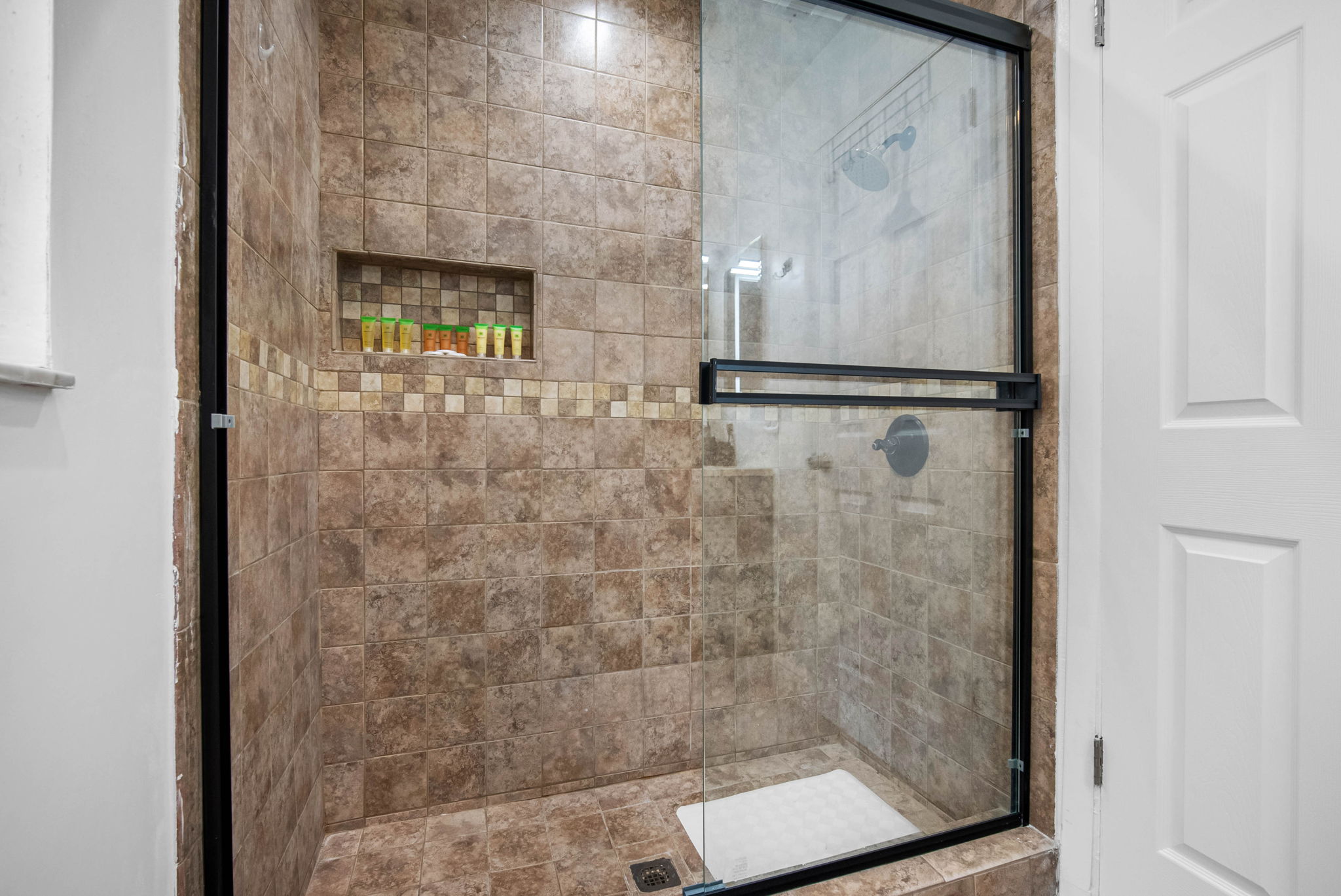Glass shower doors, quality finishes, and a framed mirror elevate this space above the average rental bath.