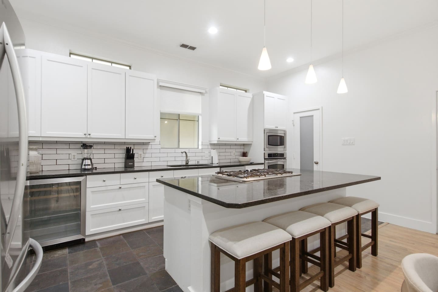 Open kitchen with pendant lighting, dark granite countertops, and island bar seating. A well-designed layout that makes cooking for a group easy, comfortable, and actually enjoyable.
