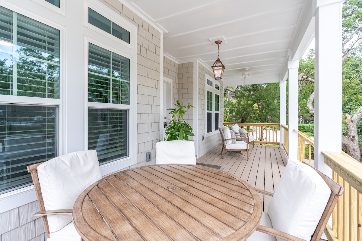Breakfast on the front porch, under the fans, before the day turns warm. A round table for four, cushioned chairs at the far end, and the oaks doing the work of a sunshade until well into the afternoon here.