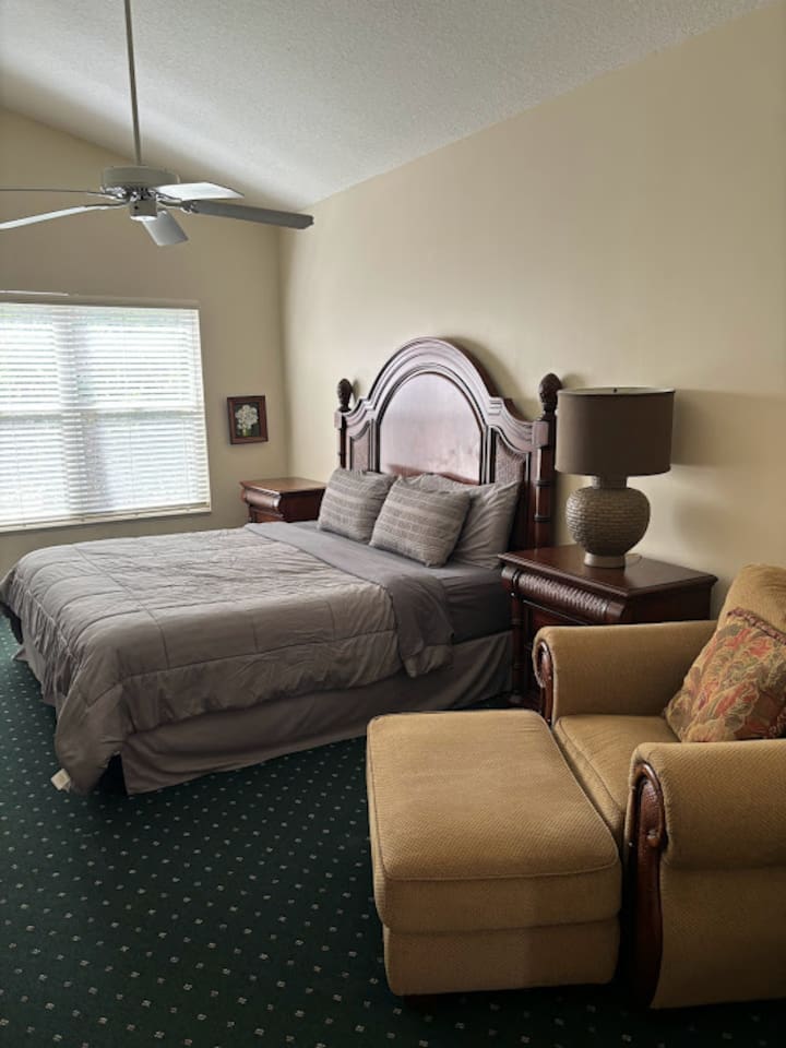 Inviting bedroom featuring a large bed, seating area, nightstand, and bright window view.