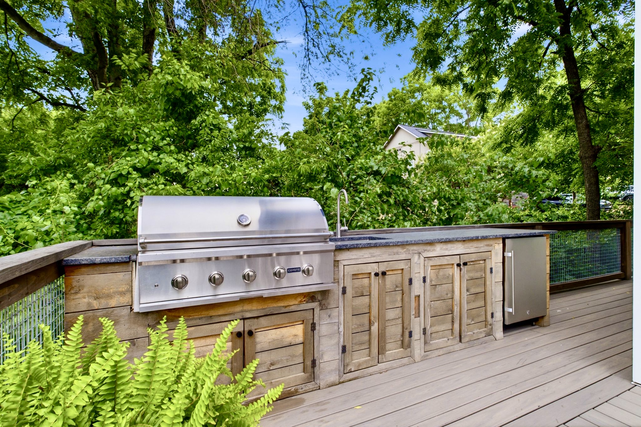 Built-in outdoor kitchen w/ a full-size grill & wood cabinetry ready for a serious cookout.
