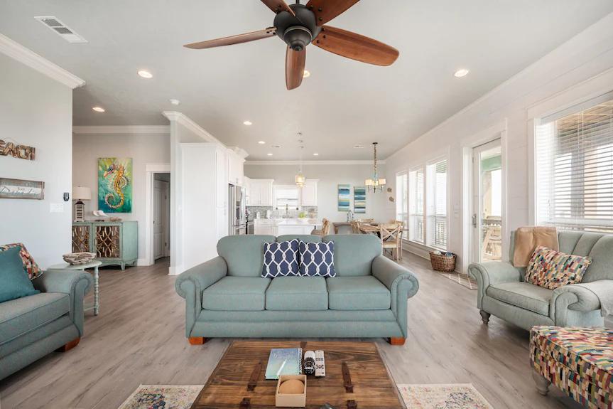 Relax in this sun-filled open-concept living space, designed for comfort and connection. With cozy seating, coastal accents, and seamless flow into the kitchen and dining area, it’s the perfect spot to unwind after a day of adventure.
