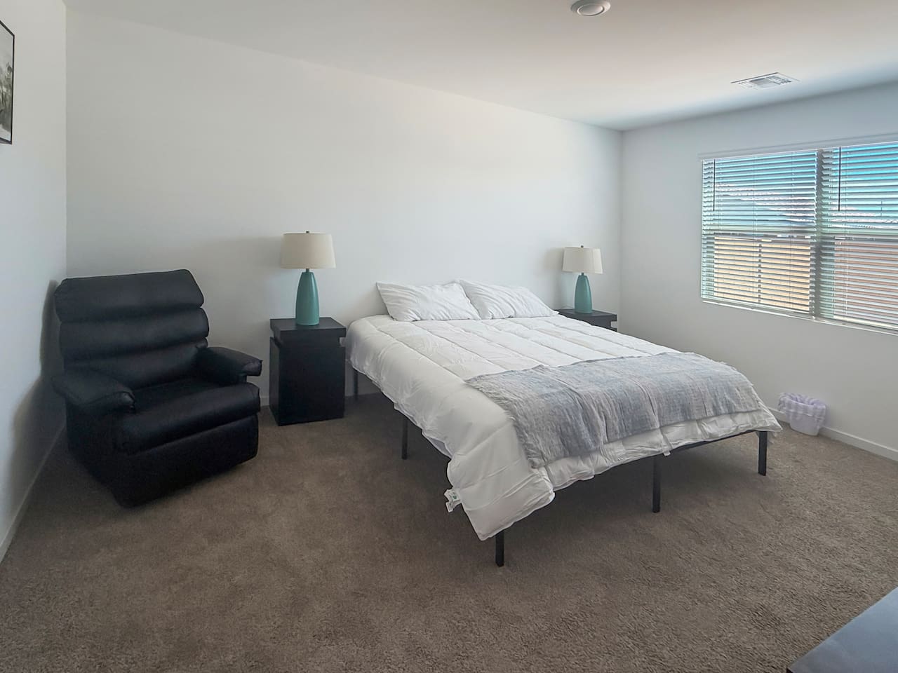 Bedroom with bed, recliner, nightstand, and windows