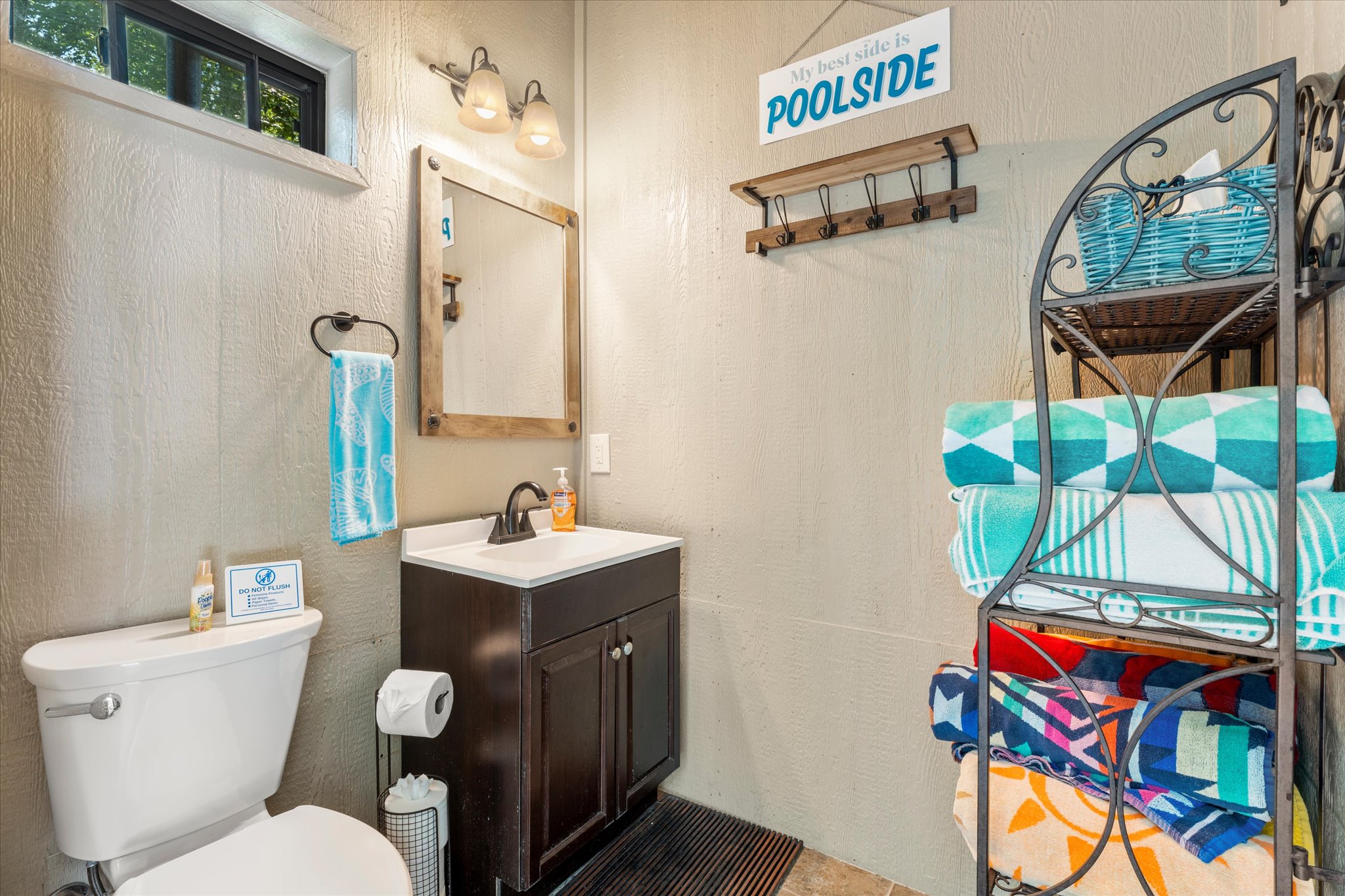 The pool house bathroom is stocked with plenty of beach towels for all guests and a "forgot it" basket filled with essentials like a first aid kit, blow dryer, and tissues, ensuring convenience and comfort by the pool.