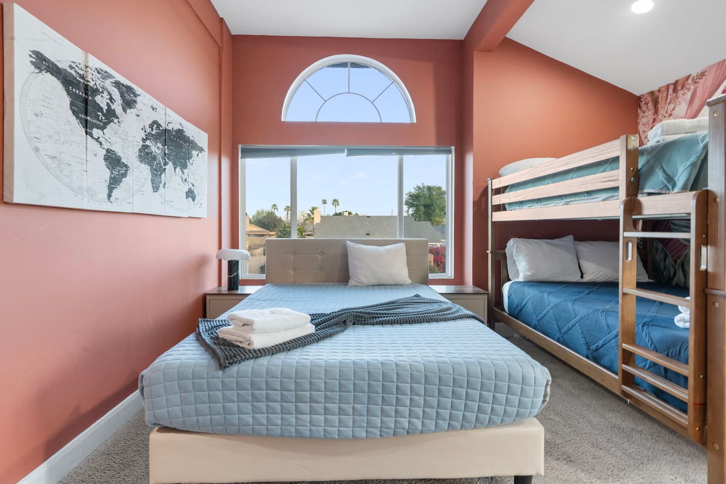Bright guest bedroom with queen bed, bunk beds, arched windows, and views.