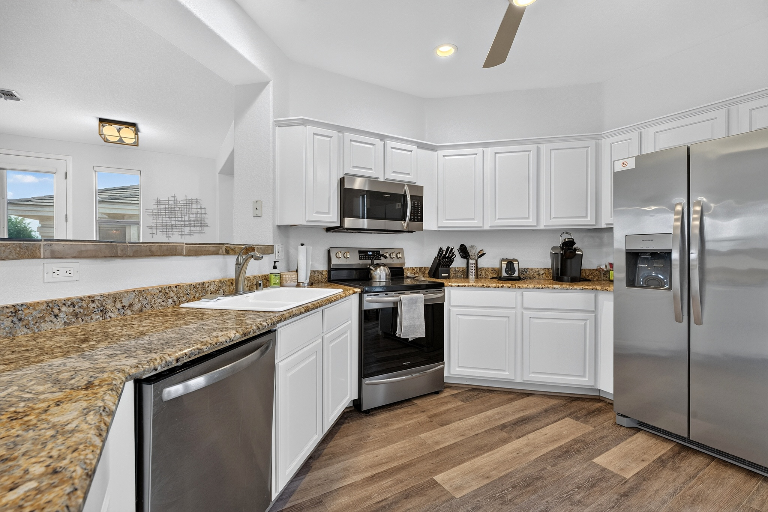 Kitchen with stainless steel appliances, dishwasher, granite counters, and open views into the living area.