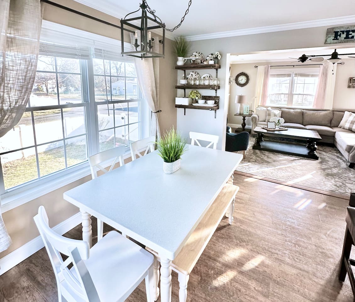 Gather for a meal at this charming dining table, bathed in natural light from the large window. The open layout allows for easy conversation with anyone relaxing in the living room, making it a wonderful spot for shared breakfasts or board games.