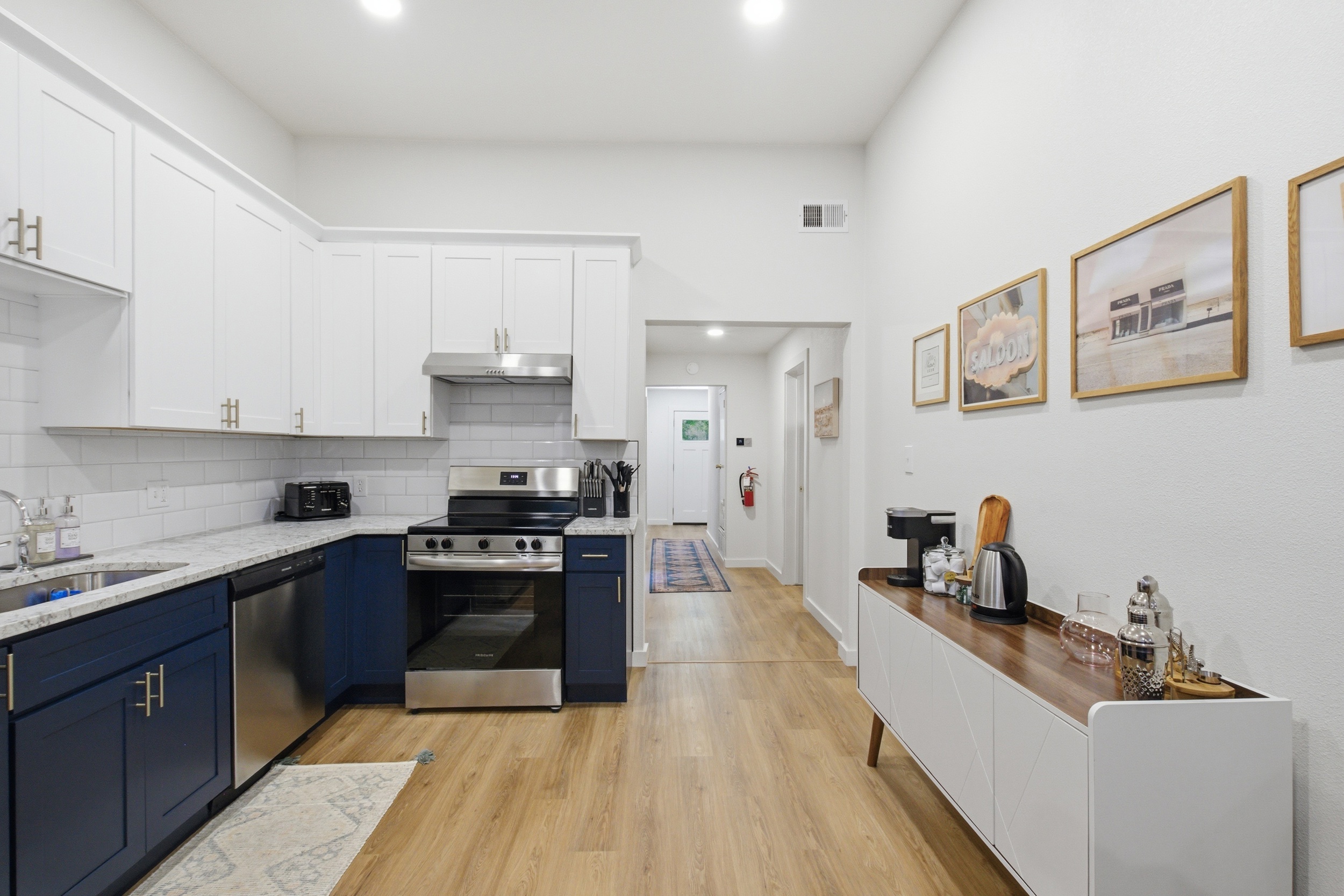 Full kitchen view from hallway showing navy island, Electric Stove, and Frigidaire Refrigerator. Premium appliance suite throughout.