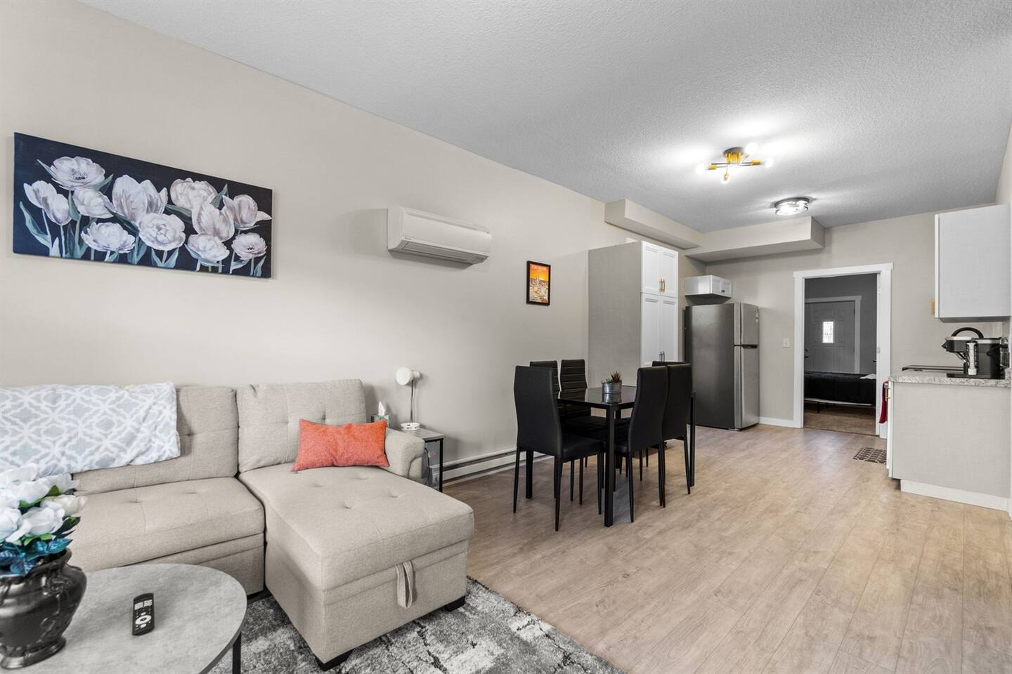 Open-concept living room with a sectional sleeper sofa, leading seamlessly into the dining area and modern kitchen for a spacious, connected feel.