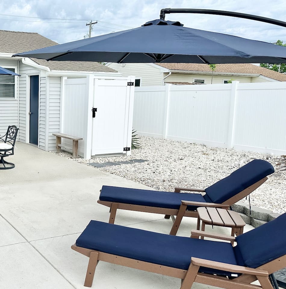 Rinse off after a day at the beach in our private outdoor shower, conveniently located right off the patio. This sun-soaked backyard area also features comfortable navy lounge chairs and a clean, fenced-in space for your privacy and relaxation.