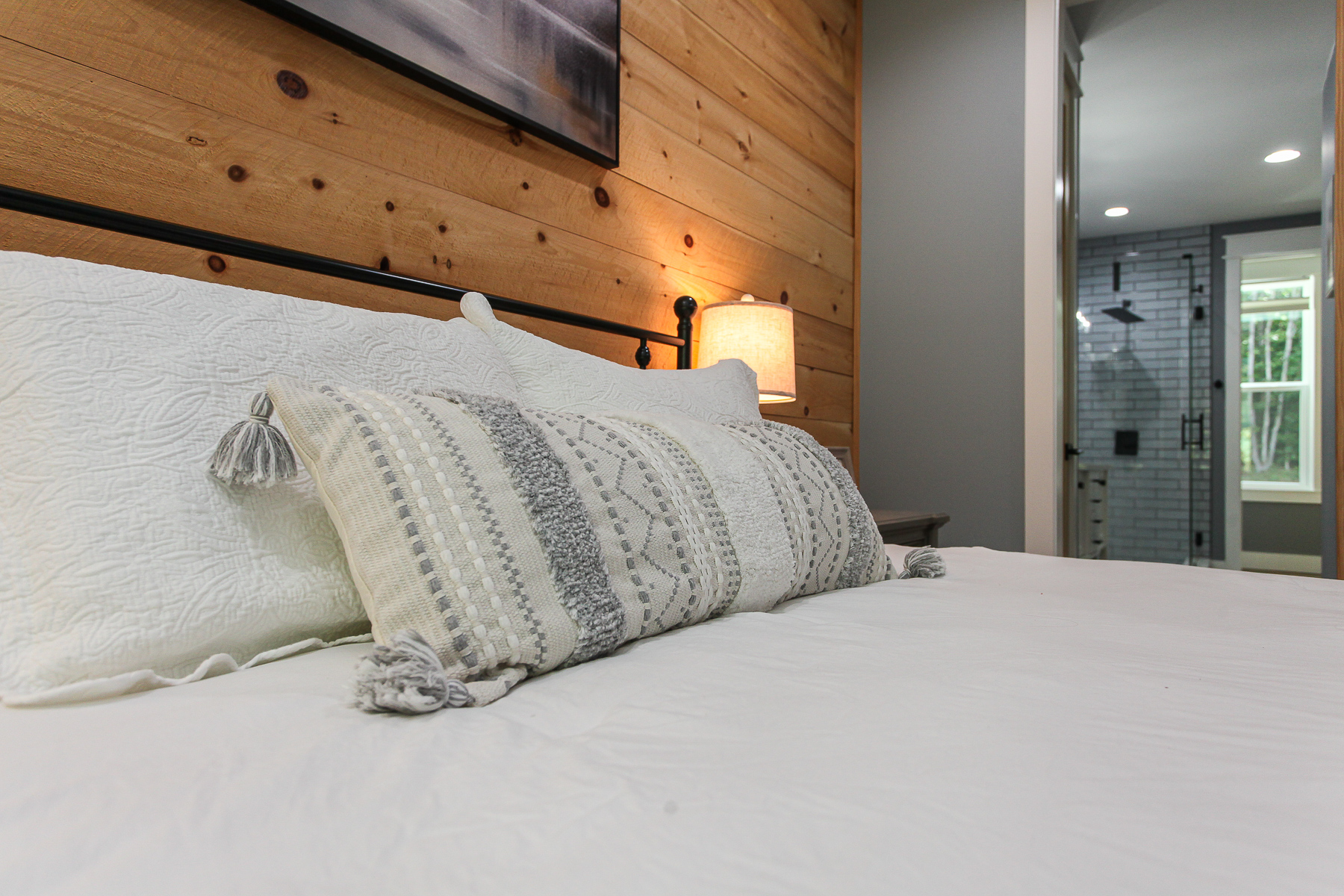 Inviting bedding and an adjoining private bathroom with a walk-in shower make the primary suite at Robbin’s Nest on Snowbird Creek a relaxing retreat.