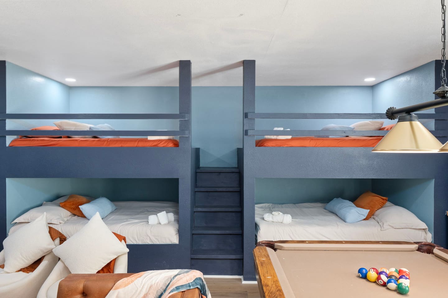 Bunk room with quad bunks, blue walls, and orange accents—sleeps up to eight guests comfortably for large groups.