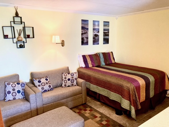 Queen bed and two sitting chairs in the bedroom/living space