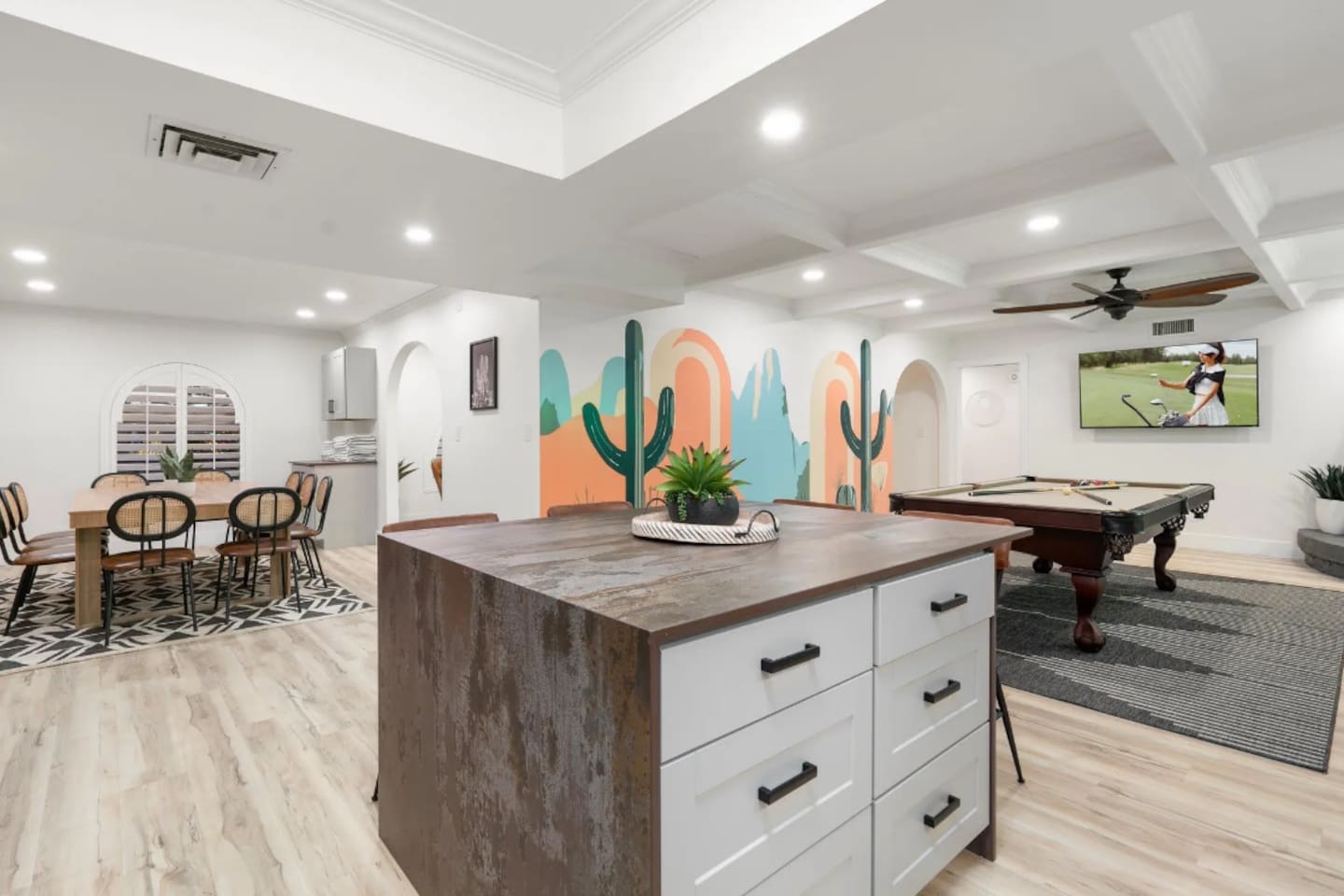 A statement island anchors the kitchen, with a hand-painted cactus mural setting a playful desert tone in the background. Just beyond, the game room invites a little friendly competition after dinner winds down.