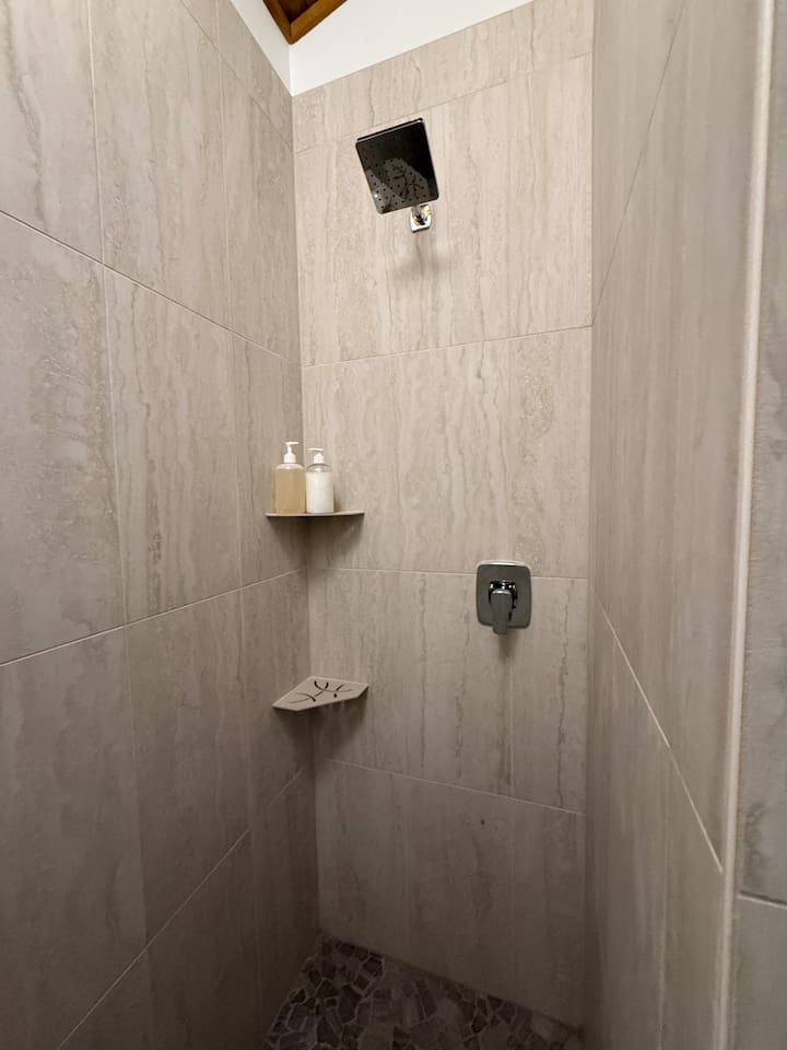 Newly renovated walk in shower with a river rock tile floor. 