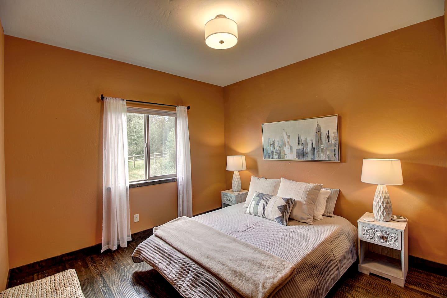 Cozy up in this warm, sunset-toned room with a plush queen bed and soft layered pillows, the perfect spot to rest up after a full day of adventure.