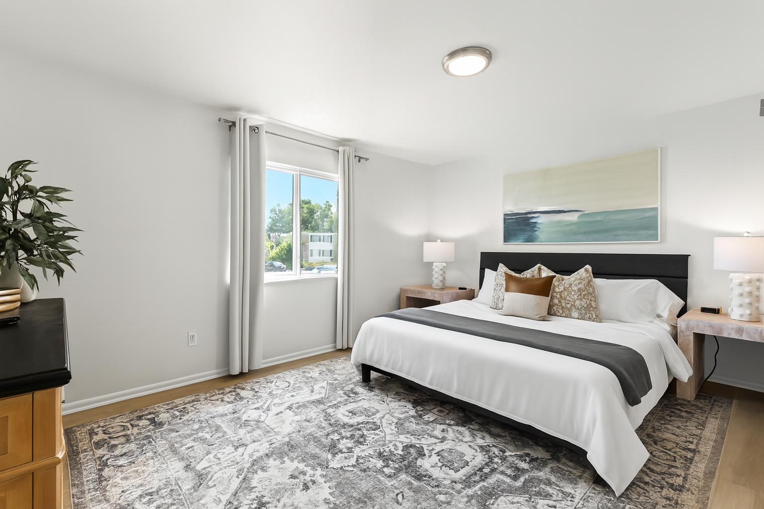 Natural light floods this spacious bedroom, offering serene views and a calm atmosphere to unwind.