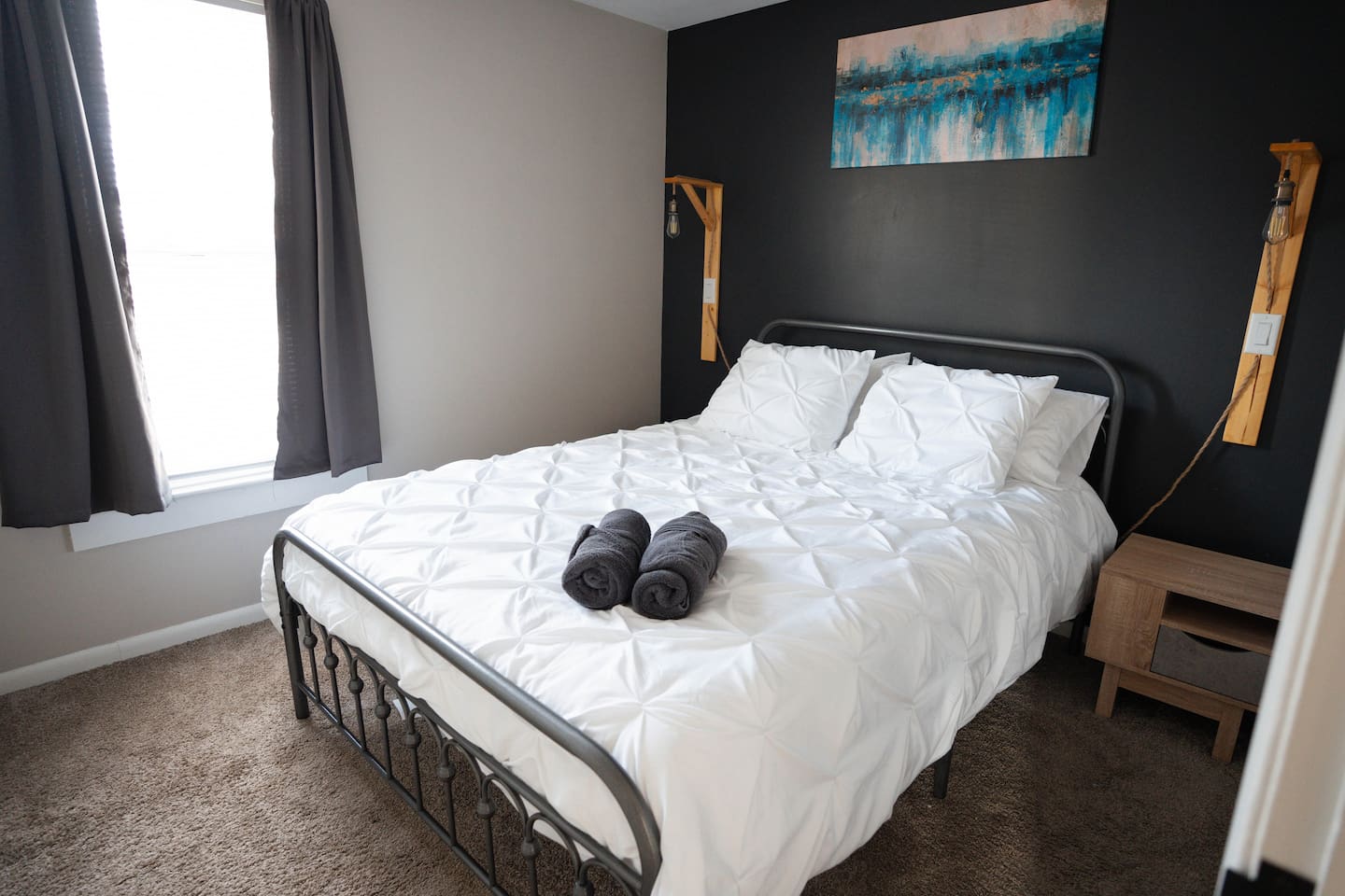 The bedroom has a comfy queen bed with fresh linens and plenty of pillows. Two nightstands with lamps make it easy to read or relax before bed. Curtains keep the space private and cozy, so you can get a good night’s rest.