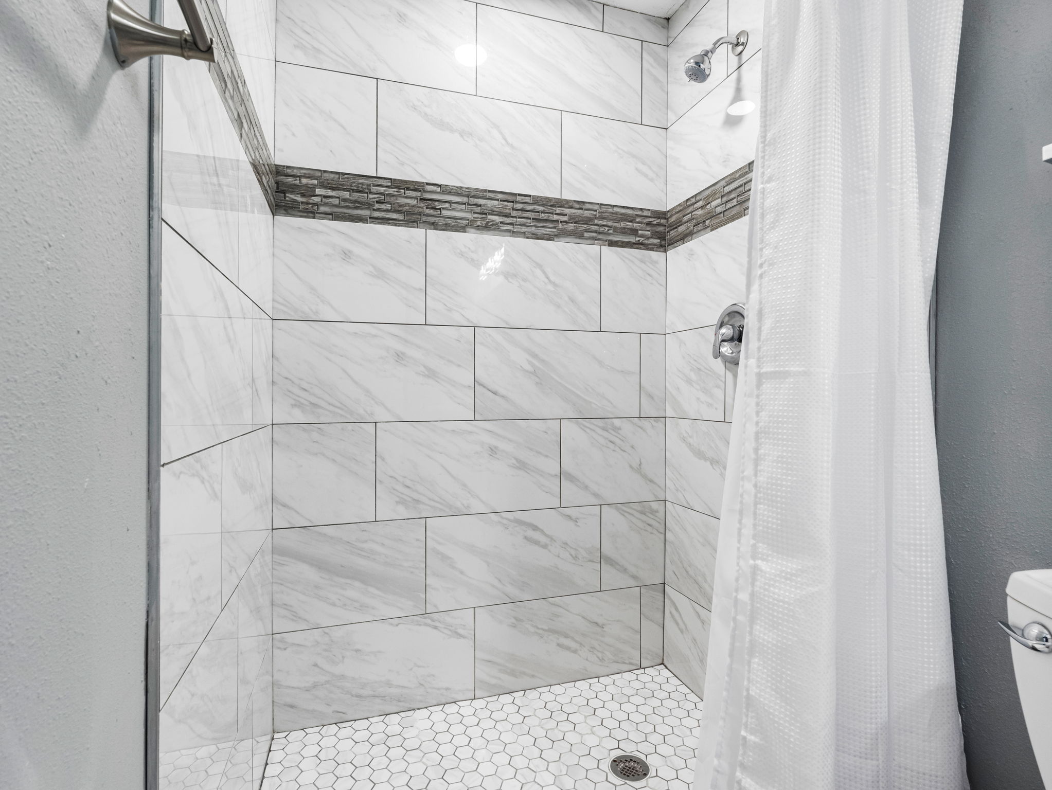From the hexagon-tiled shower floor to the granite countertop and sleek faucet, every detail is thoughtfully curated.