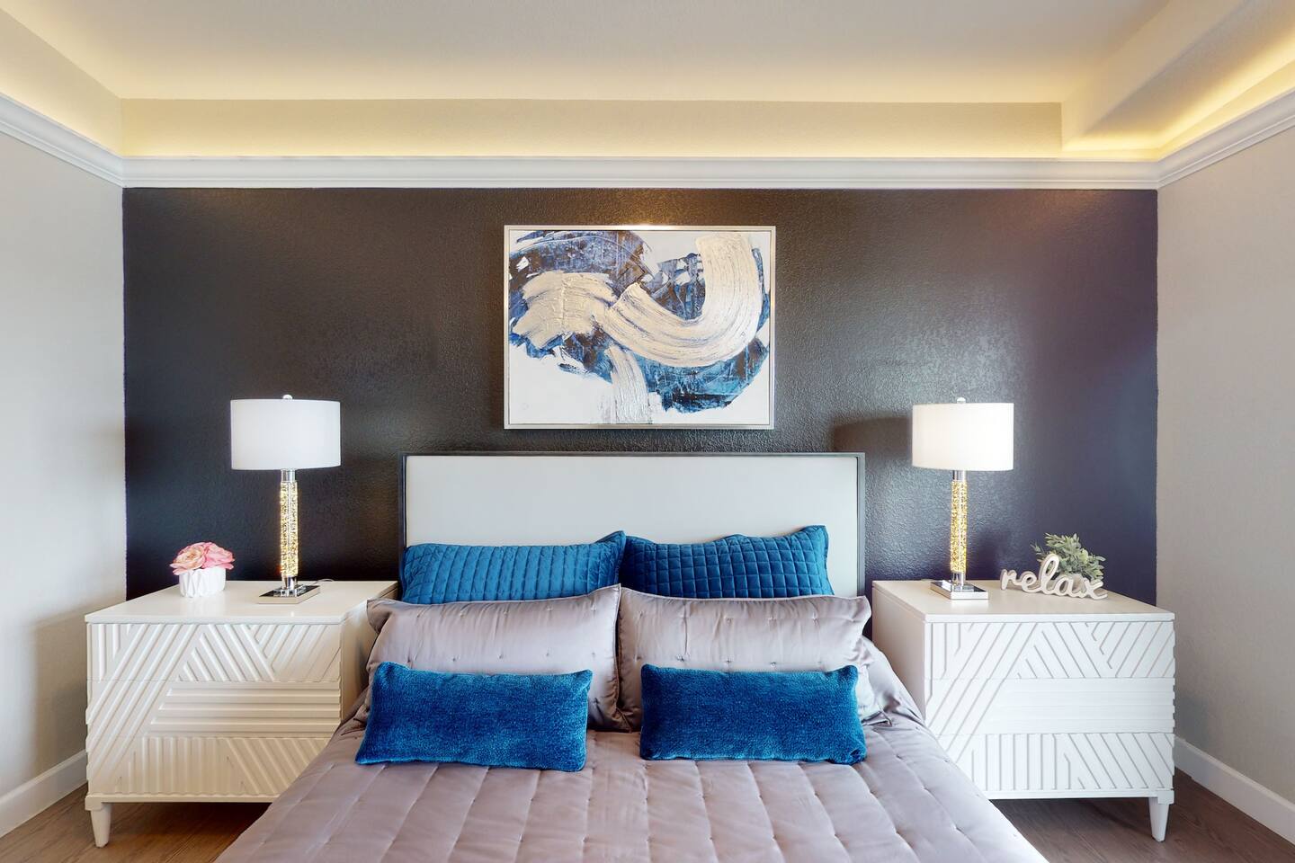 Master bedroom with modern decor, King size bed, private ensuite bathroom, large flat screen tv, surround sound system, ceiling fan, soffit lighting, sliding glass door, and access to the outdoor patio deck.