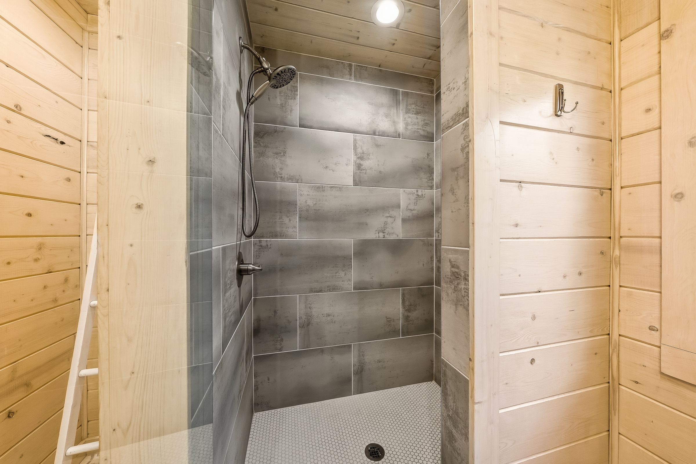 A spacious, beautifully tiled walk-in shower with warm wood accents for a relaxing rinse after a full day of adventure.