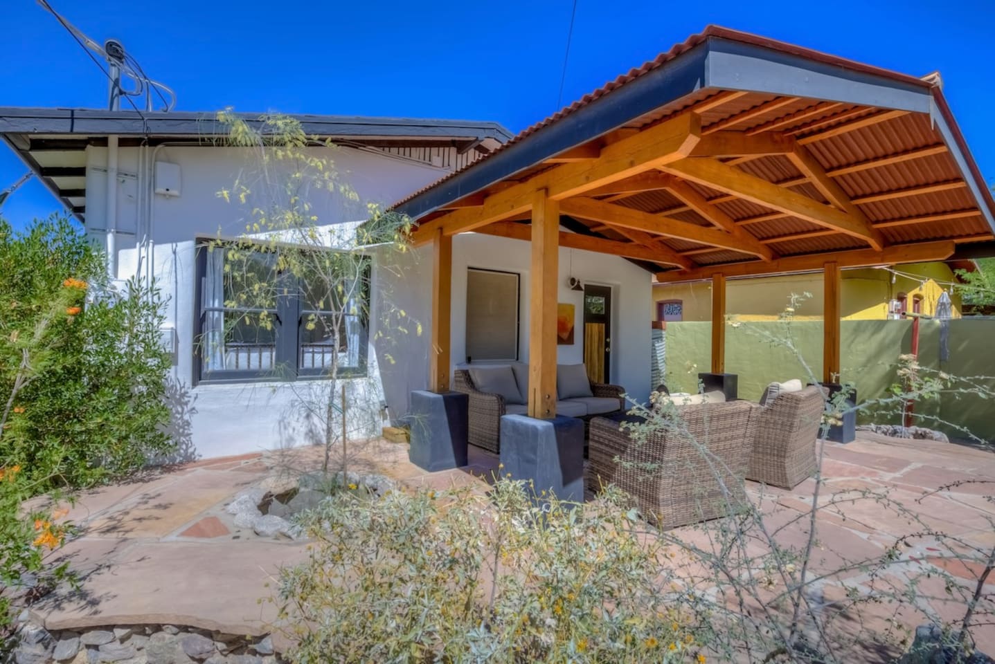 Back patio with seating area and mature desert landscaping