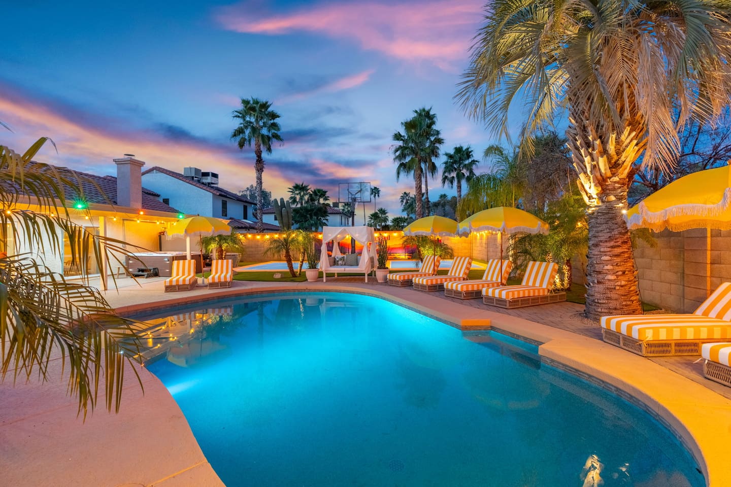 Twilight hues wash over the pool and loungers, framed by the softly lit home.