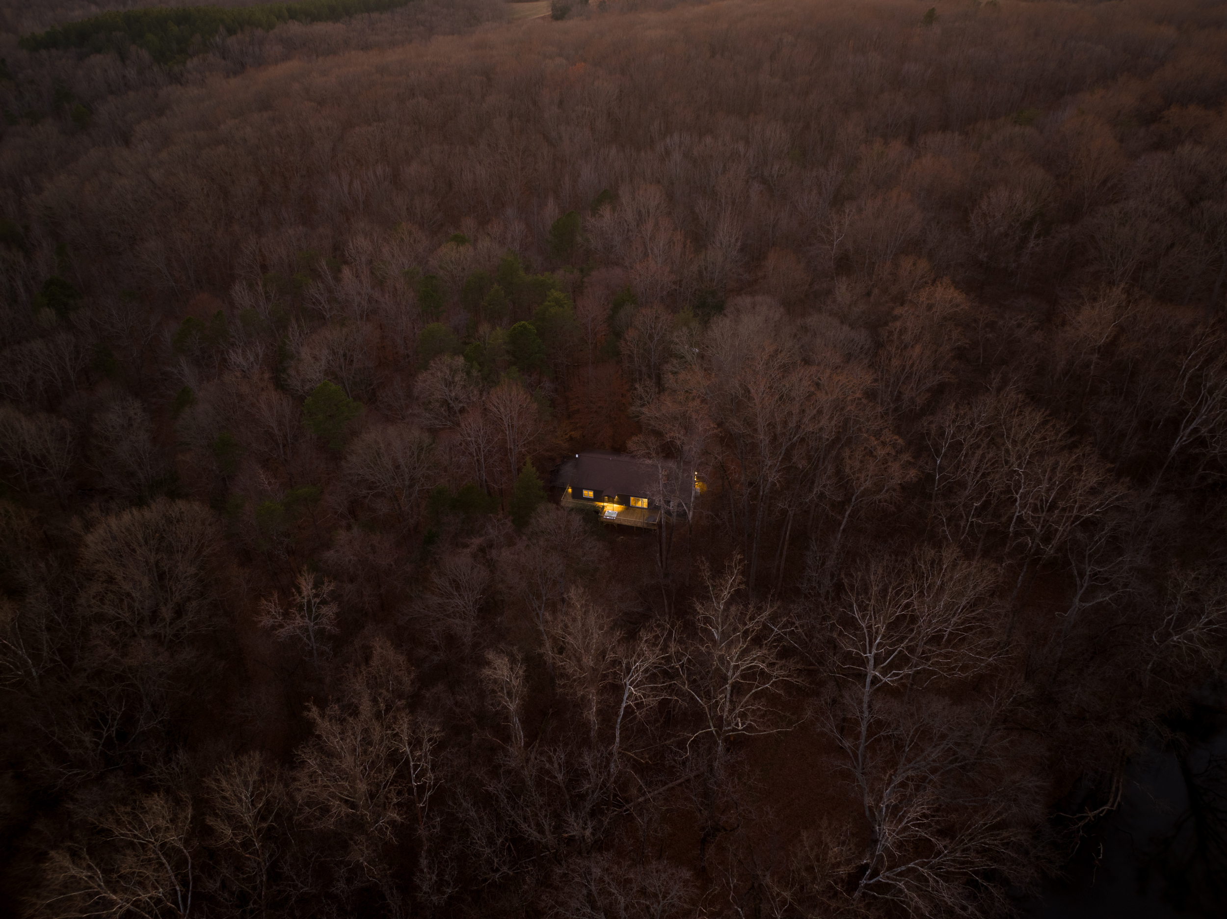 Charming Retreat: Nestled in serene woods, enjoy evening lights beckoning tranquility.